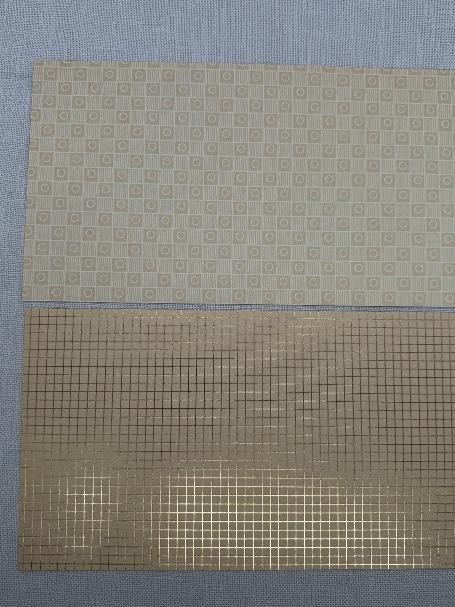 Zwei große Stücke Bastelpapier in Beige mit feinem Muster. 