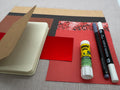 Bastelset mit Notizbuch, Stiften und Papier in verschiedenen Farben.