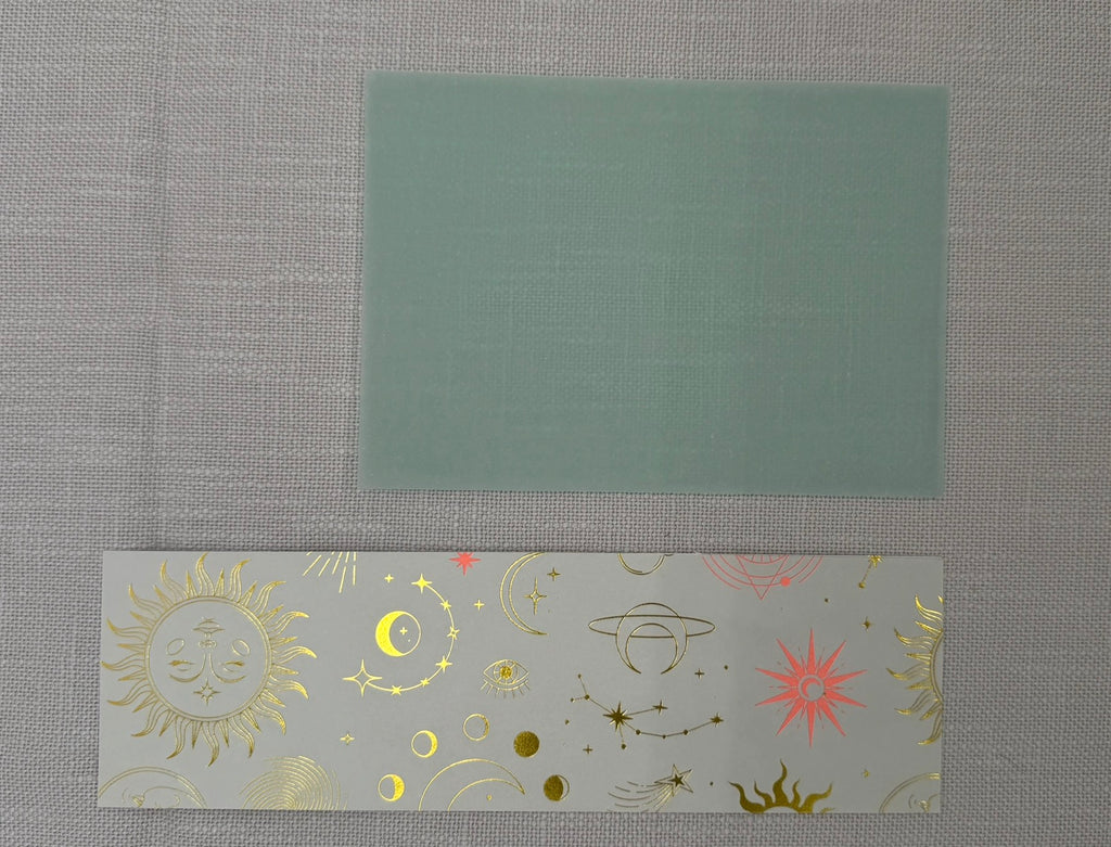 Transparentpapier in Grün und ein Stück Designpapier mit Planeten, Monden, Horoskop Gold-Pink auf weißem Hintergrund