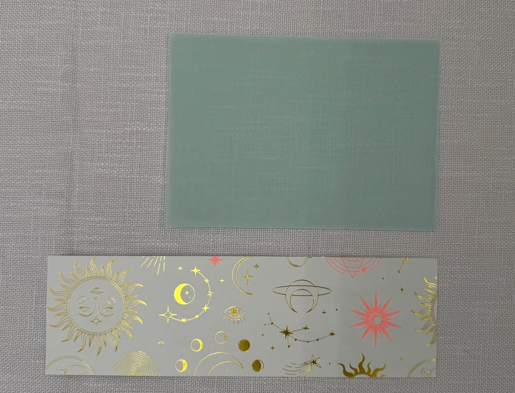 Transparentpapier in Grün und ein Stück Designpapier mit Planeten, Monden, Horoskop Gold-Pink auf weißem Hintergrund
