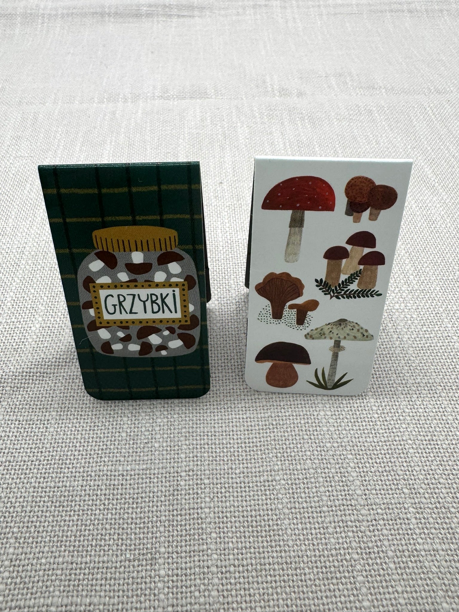 Magnet Lesezeichen Grzybki: weißer Hintergrund mit verschiedenen Pilzsorten gezeichnet und dunkler Hintergrund mit einem Glas mit eingelegten Pilzen