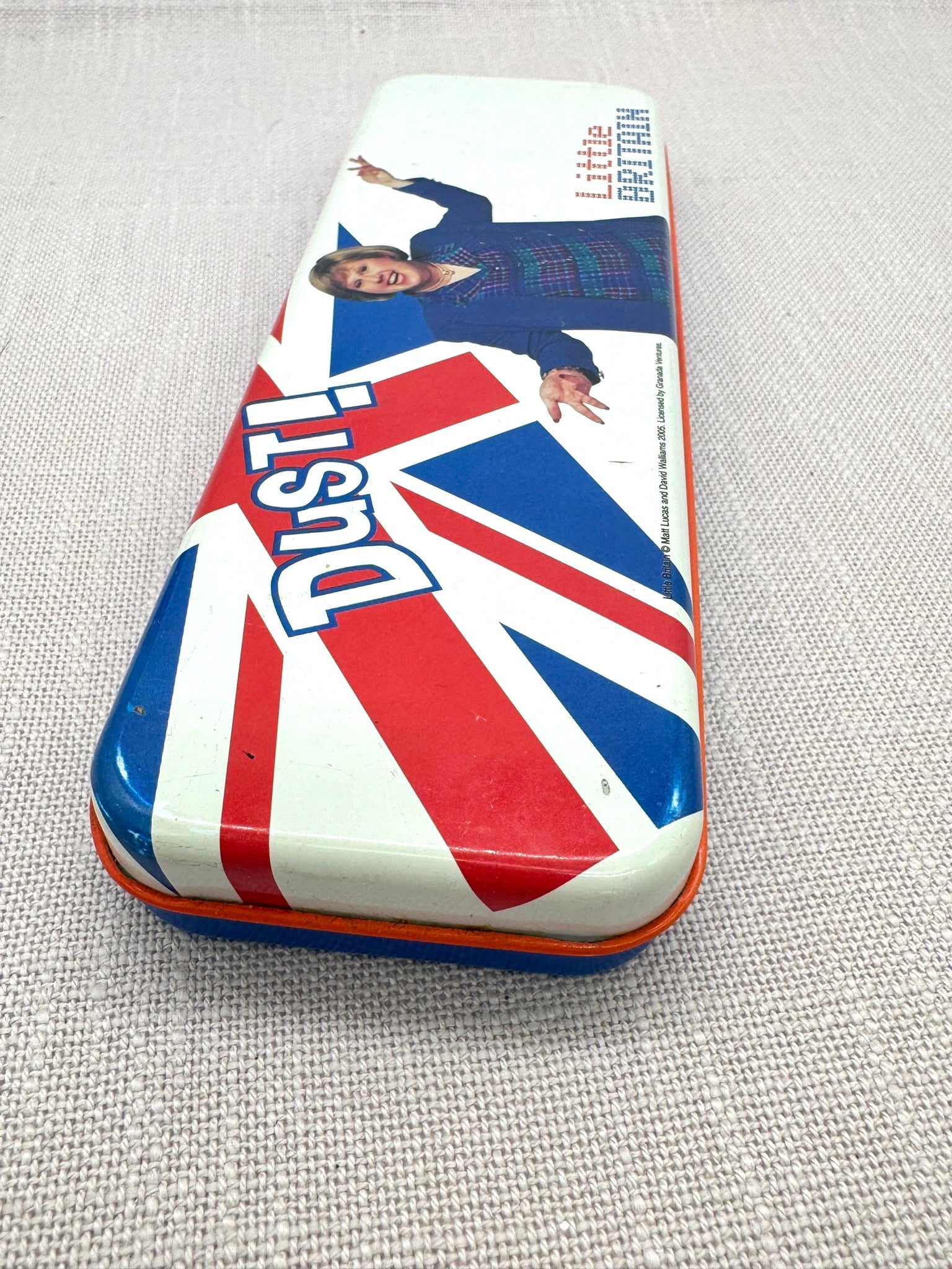 Nahaufnahme der Stiftedose: Im Vordergrund sieht man die verschlossene Dose mit der britischen Flagge und dem Wort "Dust!"