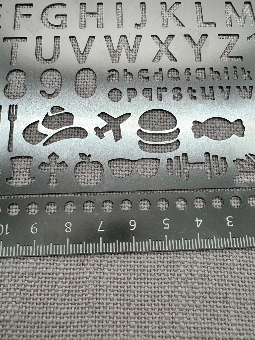 Nahaufnahme der unterschiedlichen Motive auf der Metallschablone: Buchstaben und Icons. 