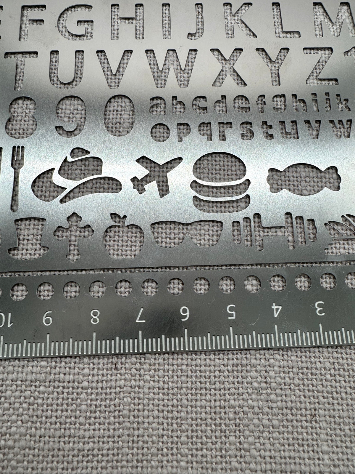 Nahaufnahme der unterschiedlichen Motive auf der Metallschablone: Buchstaben und Icons. 