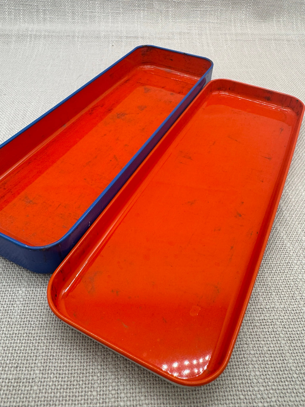 die offene Blechdose, untere und obere Hälfte. Das kräftige Rot im Inneren steht in einem Kontrast zu der blauen Unterseite. 