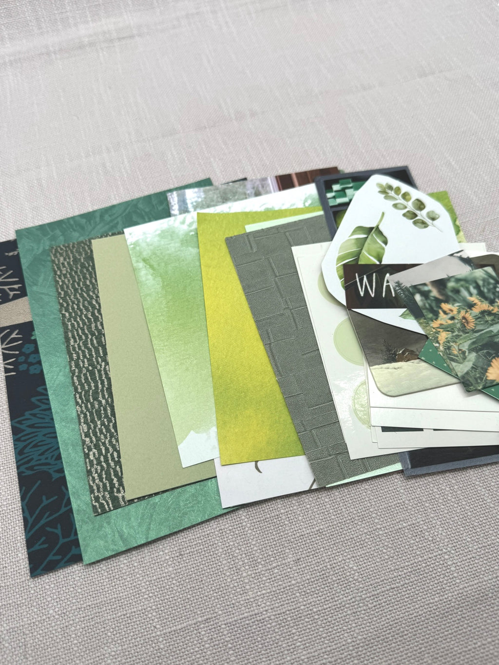 Grüne Papierauswahl: Tapetentücke, Designpapier, Origami-Papier, Sticker, Karten in verschiedenen Grüntönen.