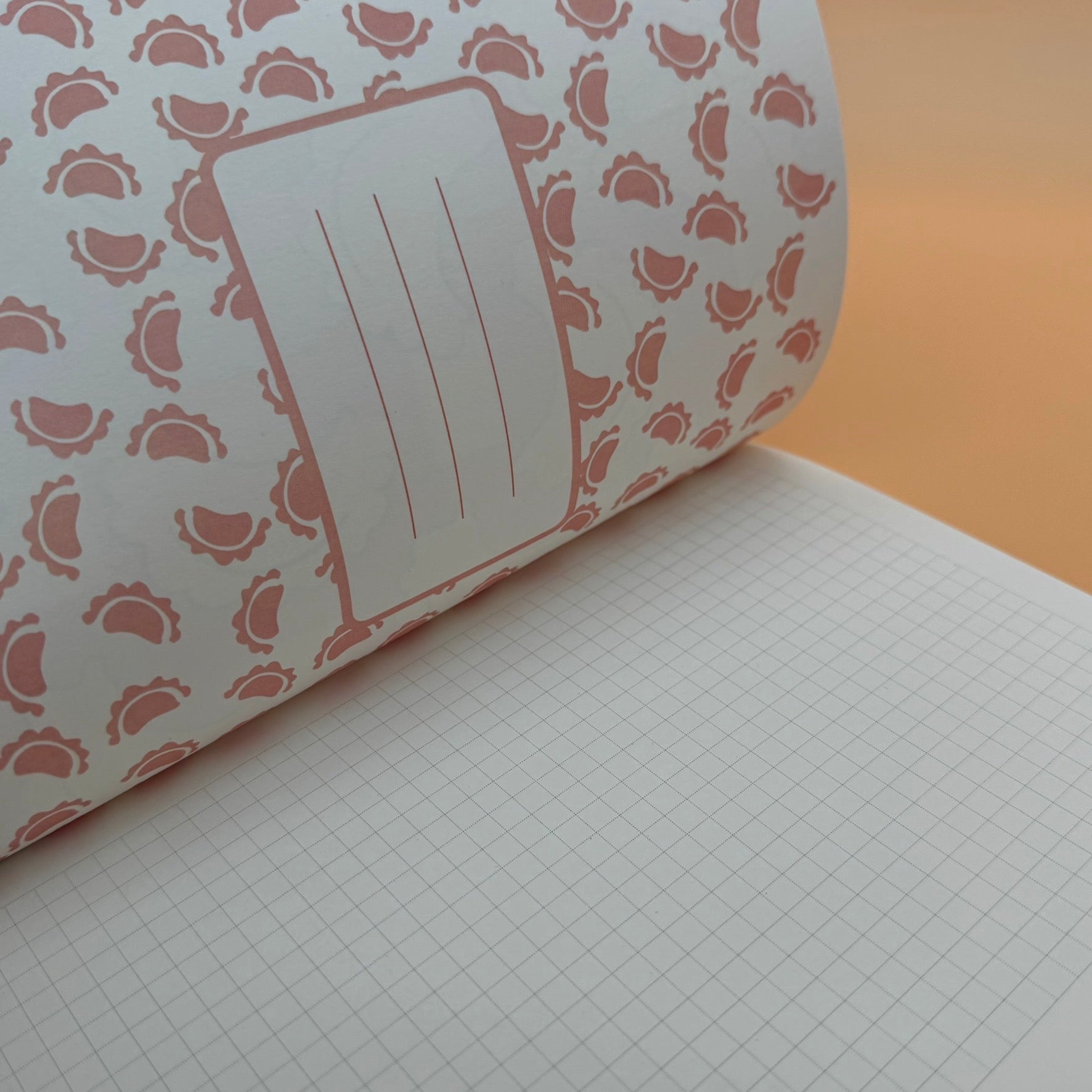 Notizheft Pierogi aufgeschlangen: kariertes Papier und die Innenseite des Covers mit kleinen Pierogi in Rot und Platz um den Namen oder Projekttitel aufzuschreiben