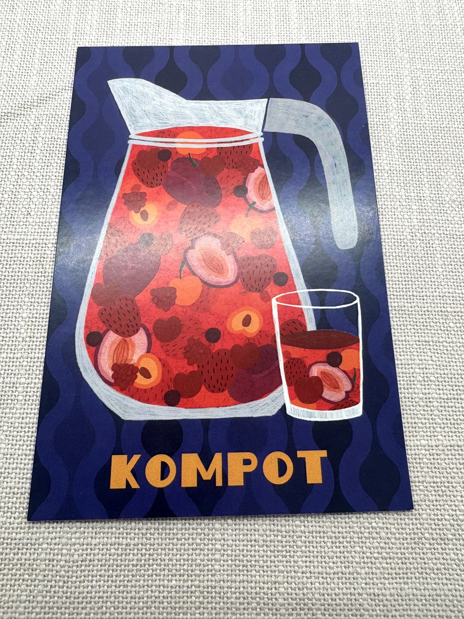 Postkarte Kompott: Eine Glaskaraffe mit roten Früchten abgebildet auf blauem Hintergrund