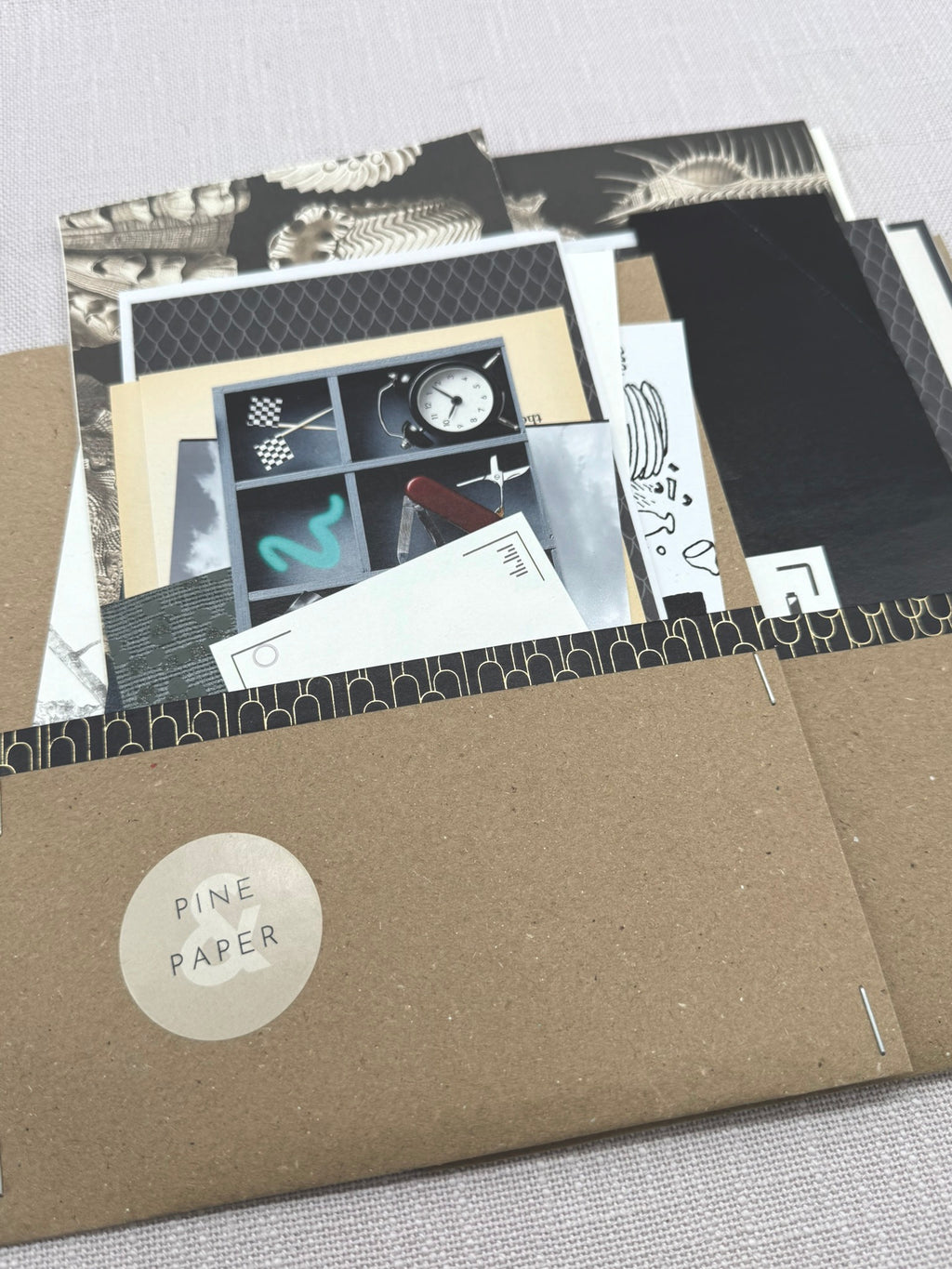 Gemischte Tüte Schnipsel mit verschiedenen Papierstücken in Schwarz und Grau. Verpackt in einen Umschlag aus Kraftpapier. 