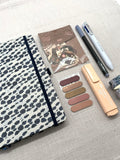 Schreibset mit einem Notizbuch, index-Streife, Sticker-Set, Textmarker, Fineliner, 4-Farben-Kugelschreiber und Washi Tapes - die einzelnen Schreibwaren sind ordentlich nebeneinander ausgelegt. Sie liegen auf einem hellen Hintergrund. 