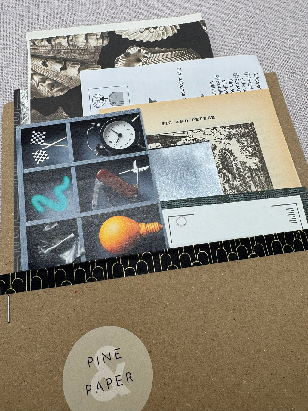 Diverse Papierbögen eingepackt in eine Tüte aus Kraftpapier. Farblich aufeinander abgestimmt in Schwarz und Grau. 