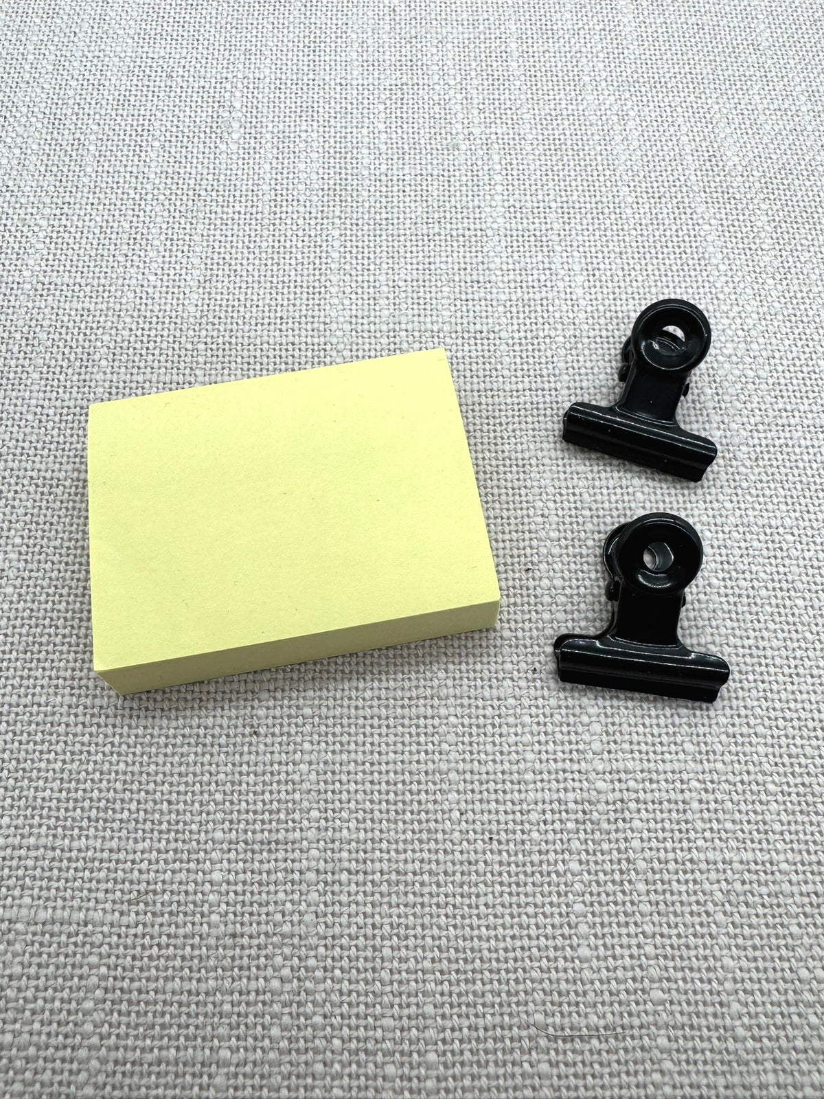 Ein kleiner Block Haftnotizen und 2 schwarze Briefklammern.
