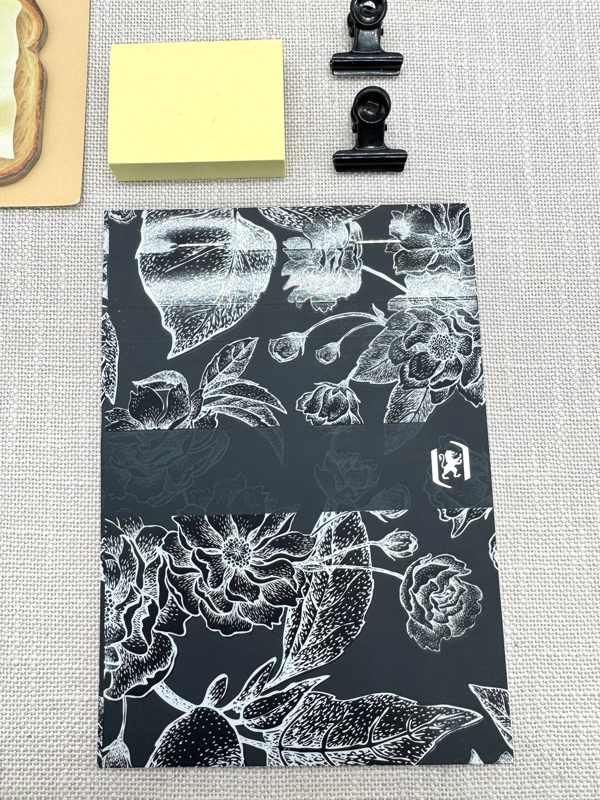 Notizblock von Oxford in Schwarz mit floralem Motiv auf dem Cover. 