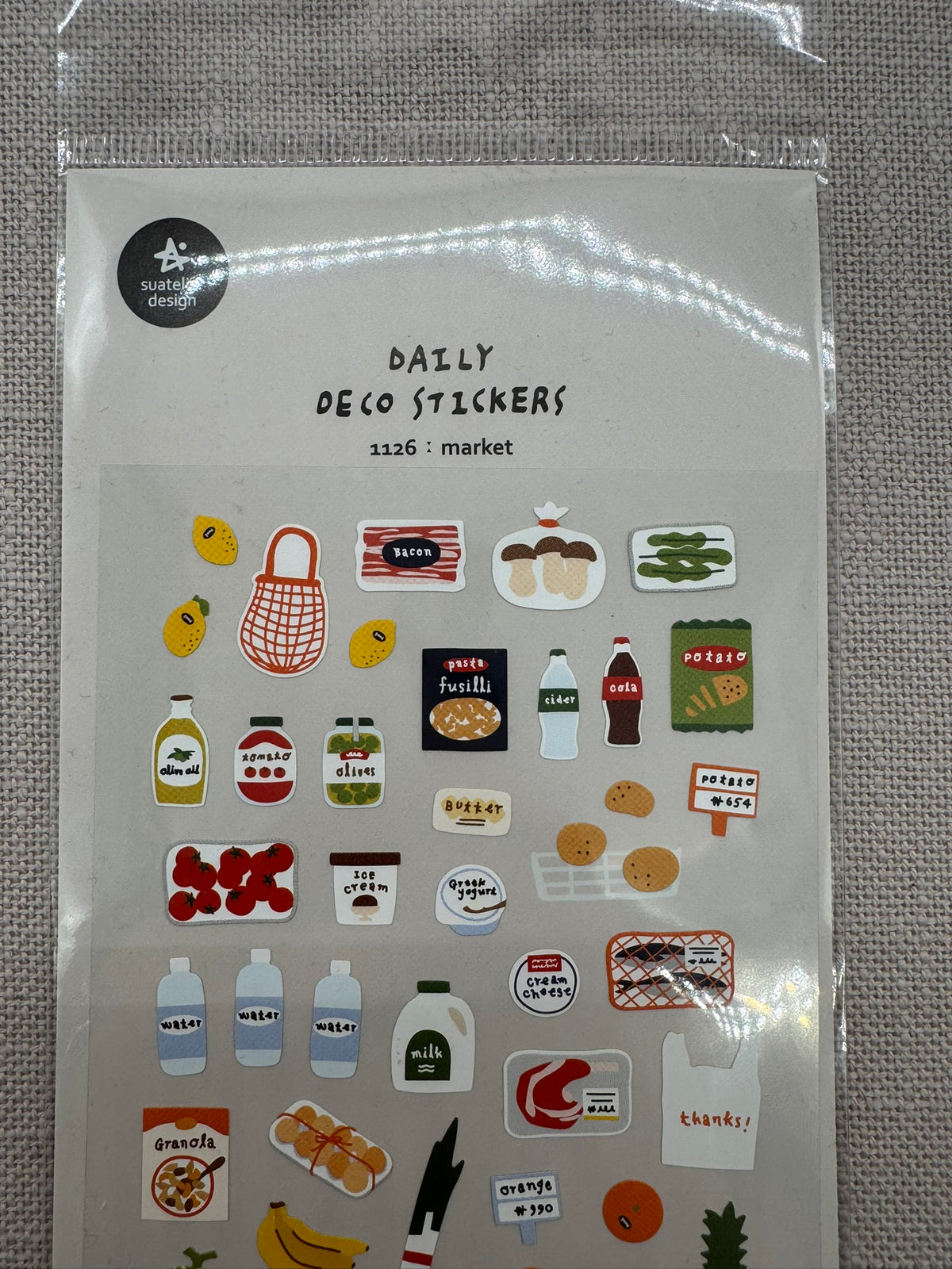 Der obere Teil der Sticker in Nahaufnahme. Daily Deco Stickers: Market. Diverse Motive: Brötchen im Korb, Einkaufstasche, Pilze, Zitronen, Wasserflaschen etc. 