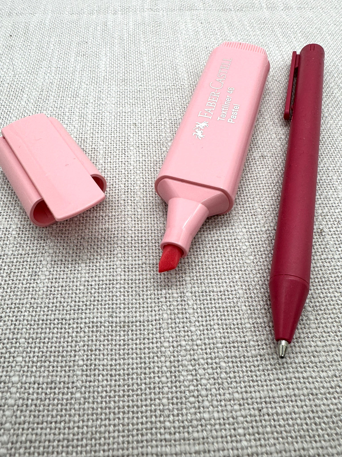 Die Schreibwarendes Sets in Nahaufnahme: ein Textmarker von Faber-Castell in zart rosa und ein Kugelschreiber aus Weizenstroh.