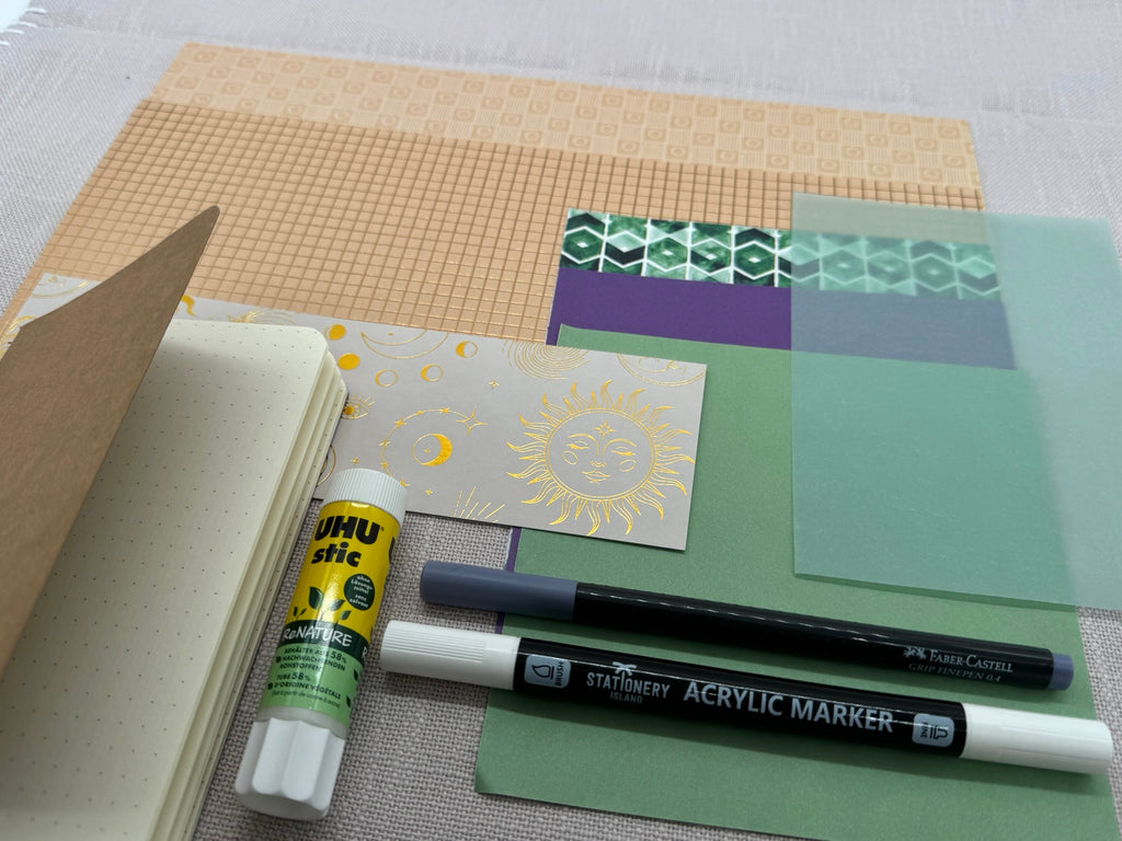 Starter-Set für Scrapbooking mit diversen Designpapieren in Grün und Beige, Stiften, einem Klebe-Stick und einem A6 Notizbuch mit Cover aus Kraftpapier zum Selbstgestalten.