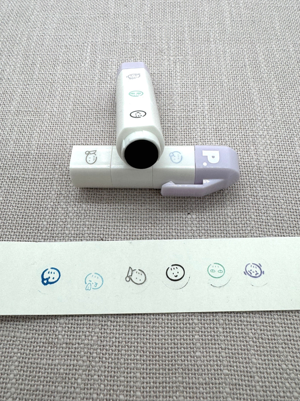 Die kleinen Stempel kann man zu einem Stift zusammenstappeln. Sie sind selbstfärbernd. Im Vordergrund sieht man die einzelnen Motive auf einem kleinen Zettel gestempelt. 
