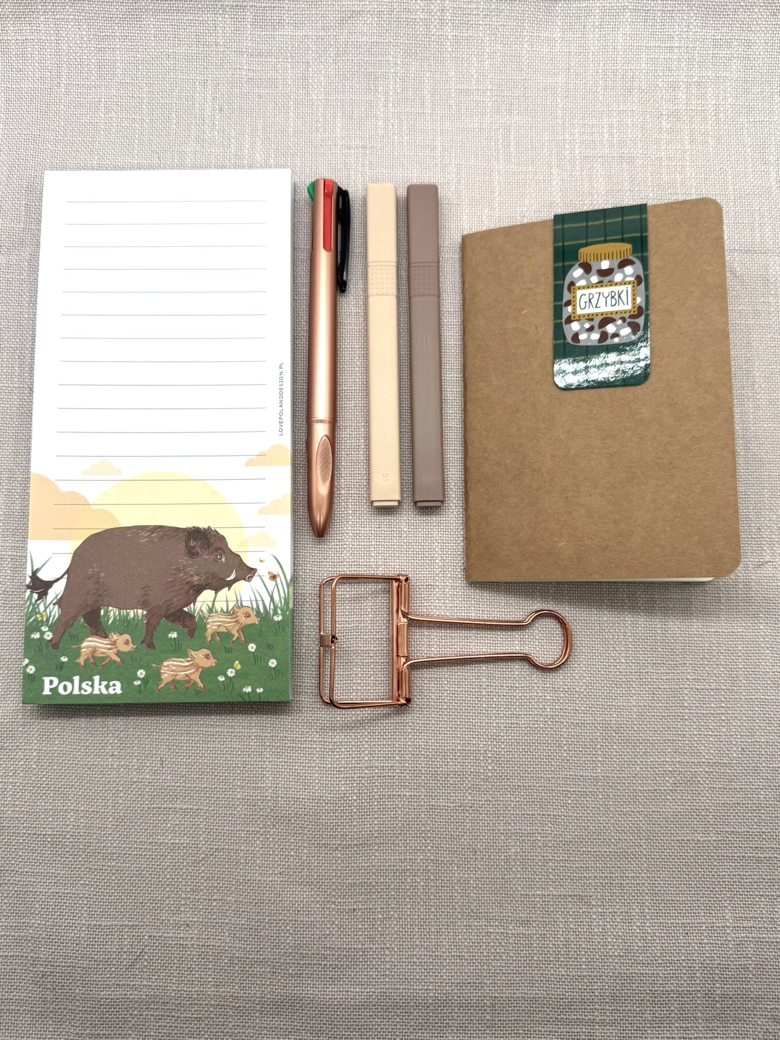 Die zweite Version von dem Set hat Textmarker in beige und braun, sowie eine rosegoldene Foldback-Klammer. Auf dem Lesezeichen sieht man eingelegte Pilze in einem Glas. Der Notizblock, das Notizheft und der Kugelschreiber sind gleich wie in der ersten Version. 