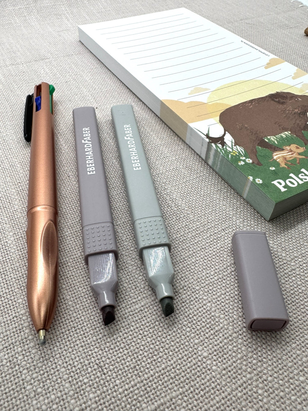 Nahaufnahme der Stifte: ein metallic-brauner Kugelschreiber und zwei Textmarker in Pastellfarben. 