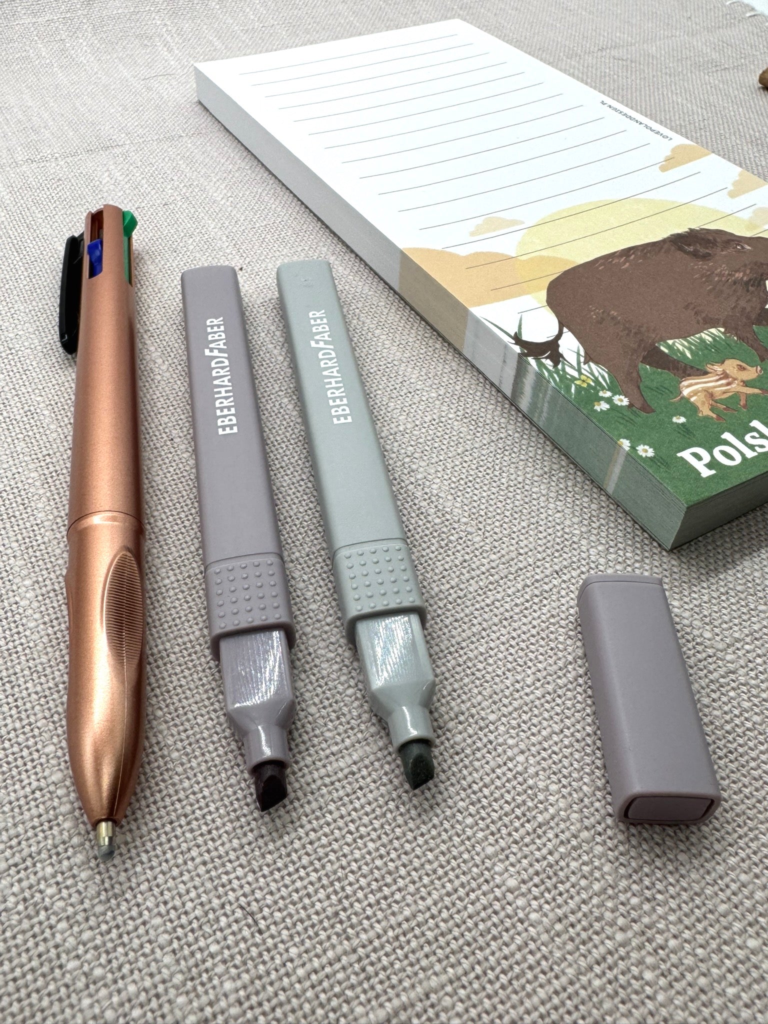 Nahaufnahme der Stifte: ein metallic-brauner Kugelschreiber und zwei Textmarker in Pastellfarben. 
