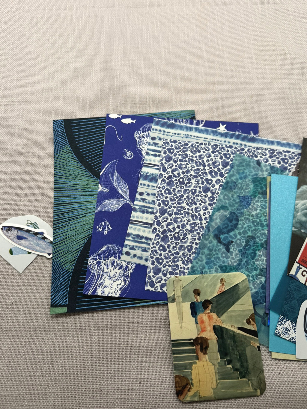 Die größeren Stücke aus dem Papierset: Tapetenstücke, Geschenkpapier, Origami-Papier, Transparentapier und daneben ein paar kleinere Sticker. 