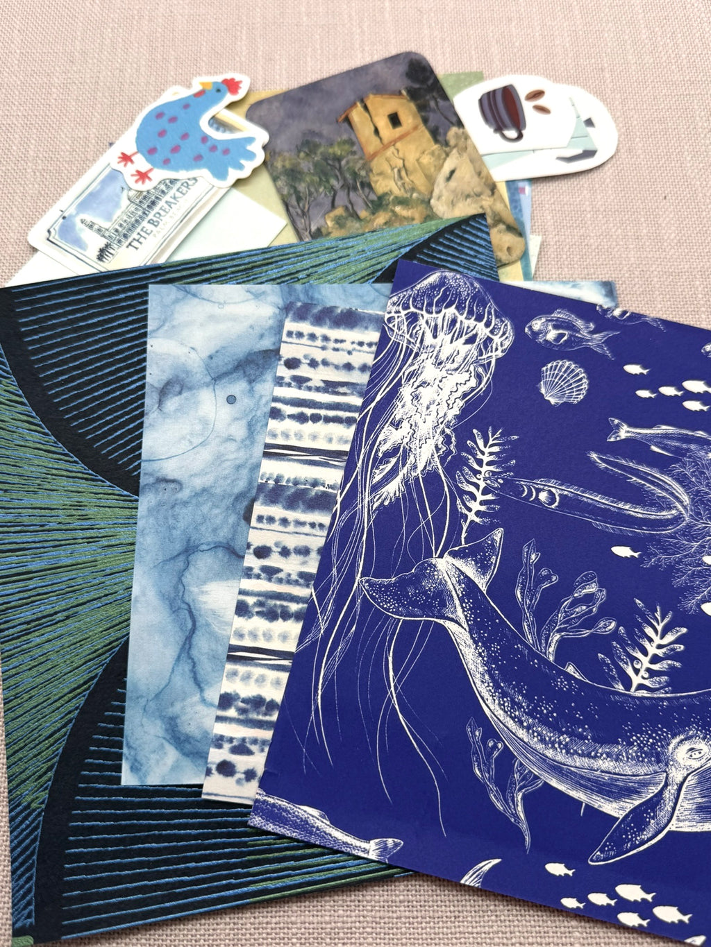 Im Vordergrund sieht man größere Papiertücke mit verschiedenen Mustern, im Hintergrund sind blaue Sticker.