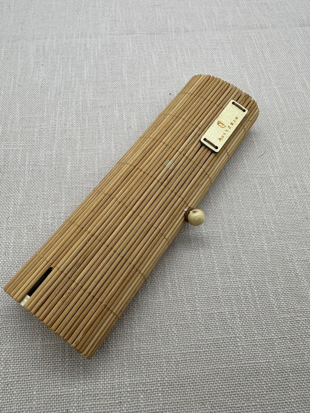 Ein Etui aus kleinen Holzstäbchen mit einem Verschluss aus Gummi und einem Holzknopf